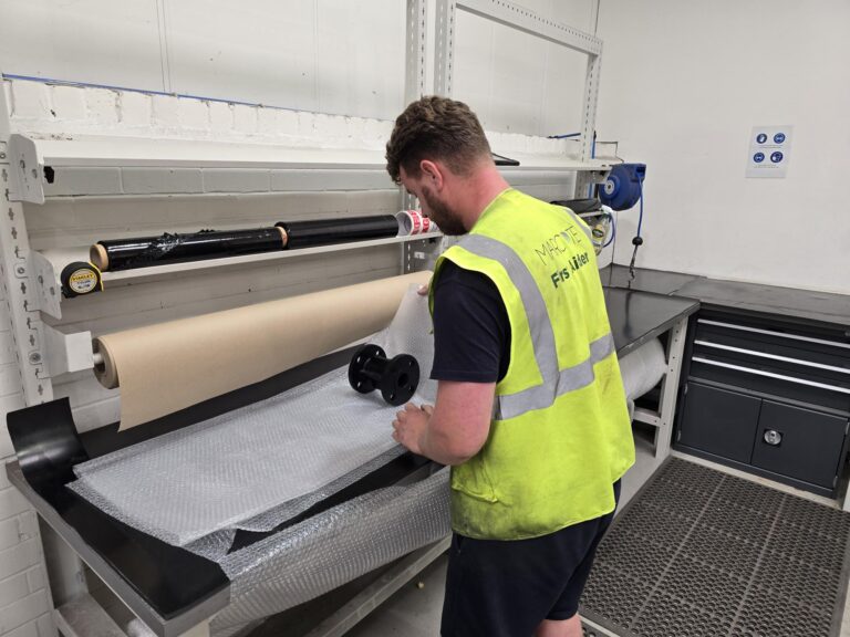 A marcote professional works on an industrial coating machine in a high-vis jacket.